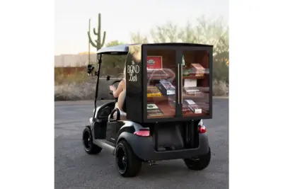 Black golf-cart with a glass-fronted cabinet on the back displaying cigars, labeled The Bond Bar